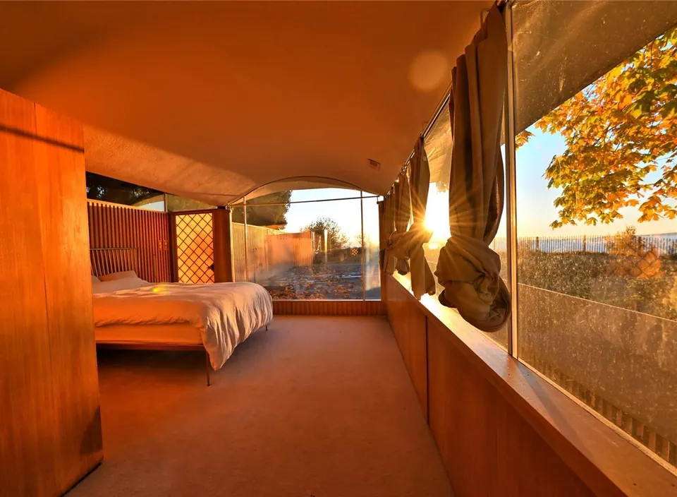 Wood-lined Filberg House bedroom with windows toward the coast.