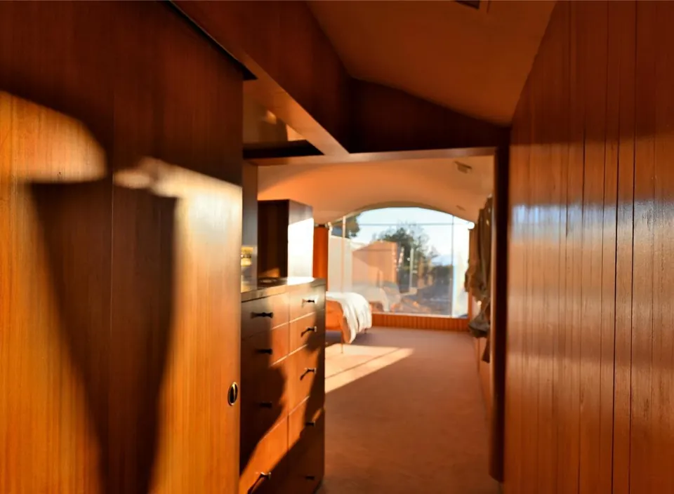Warm cedar-lined passage leading toward a bright room in the Filberg House.