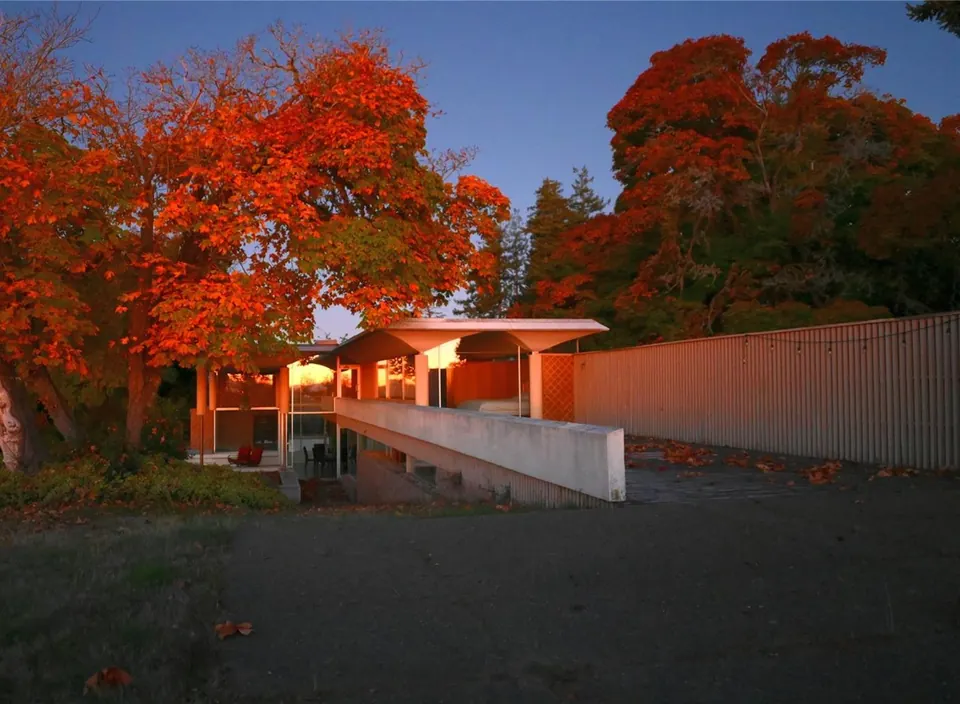 Illuminated entrance to the Filberg House at dusk amid autumn trees.