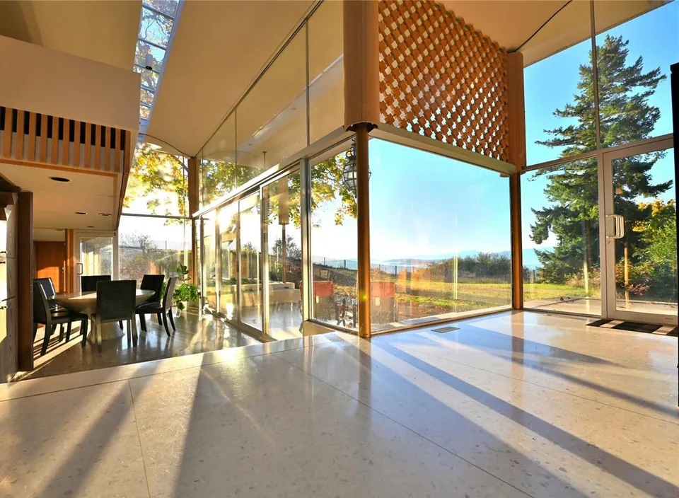 Sunlit Filberg House living room with tall glass walls looking toward the coast.