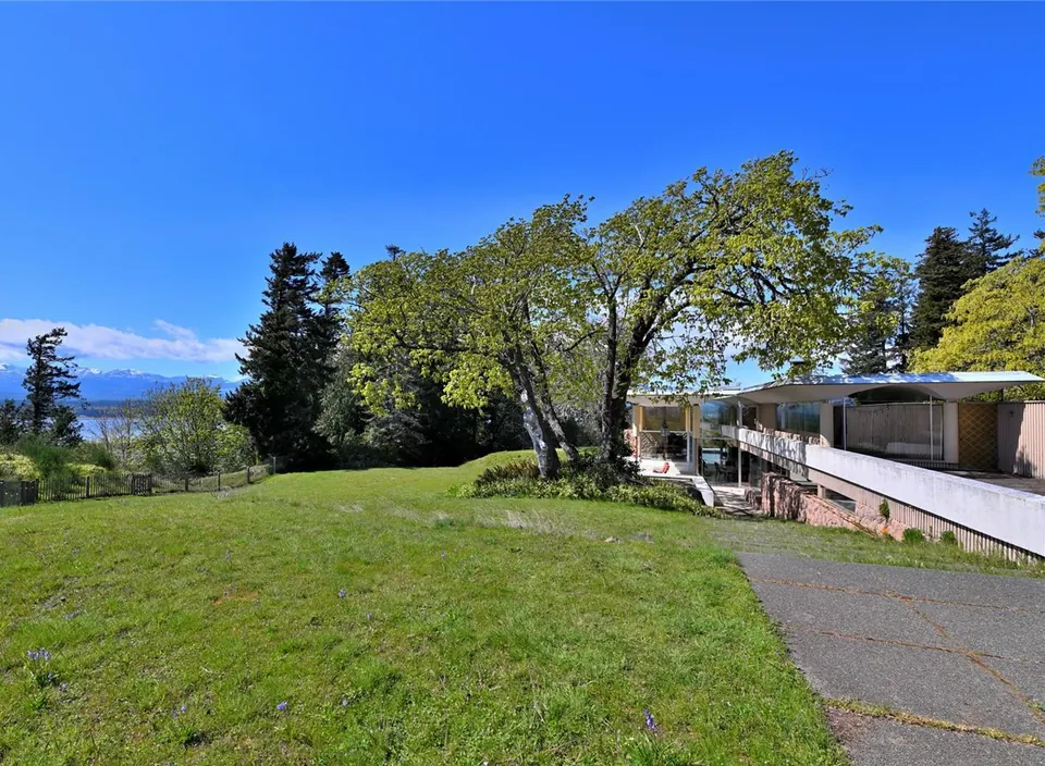 The Filberg House beyond a lawn with ocean and mountains in the distance.