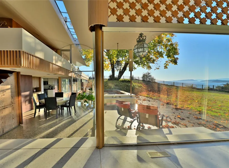 Sunlight crossing the Filberg House interior beside cedar screens and glass.